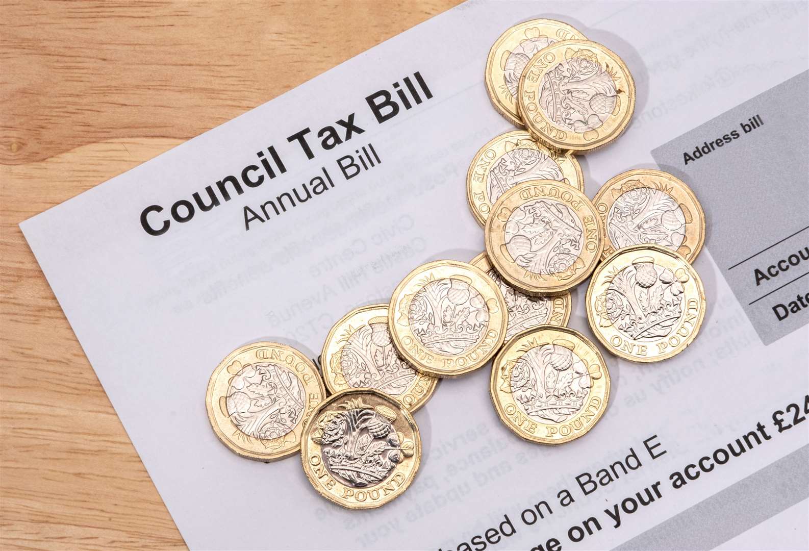 UK one pound coins placed on a Council Tax Bill.