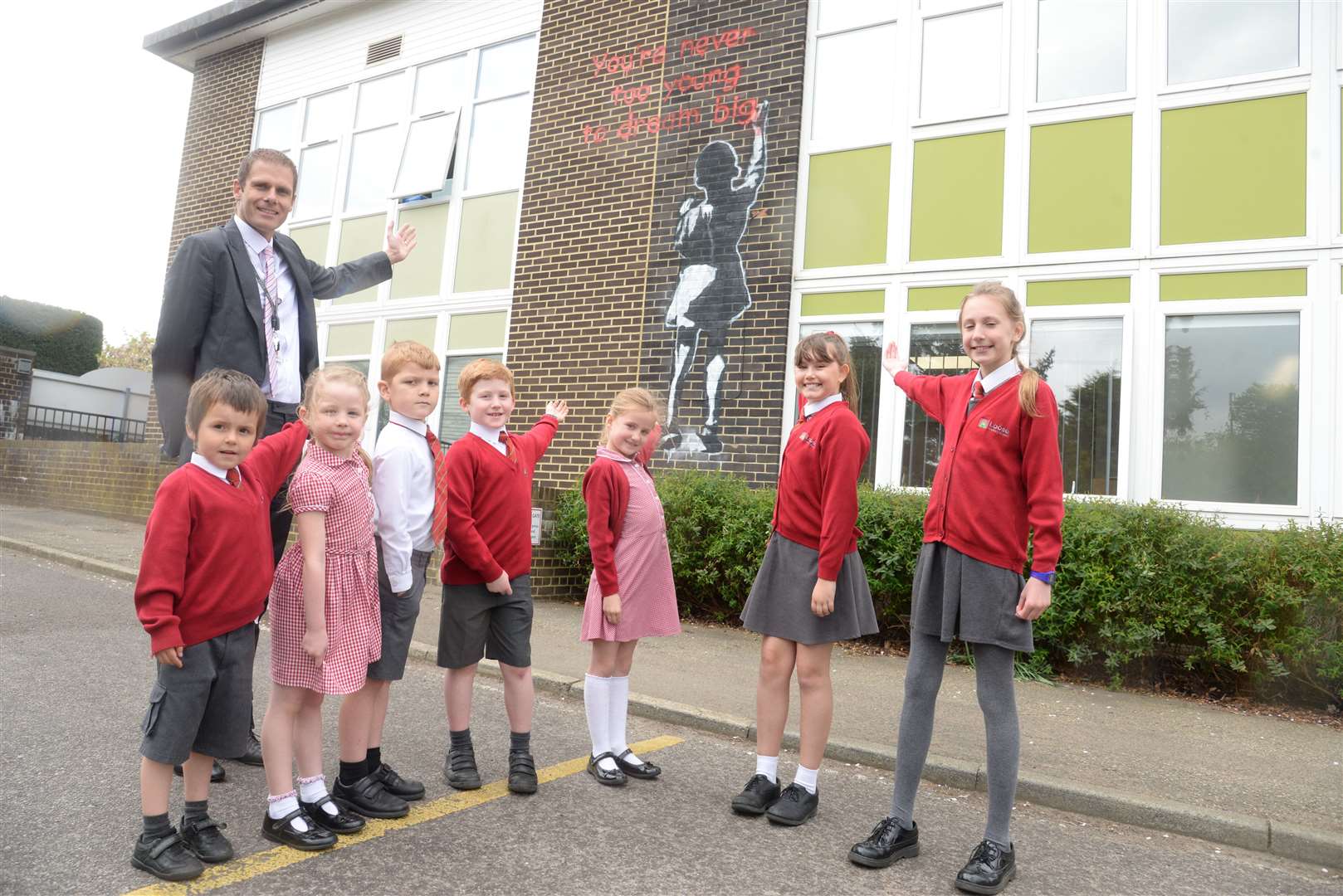 Darren Webb, executive head with some of his pupils and the Banksy-style graffiti at Loose Primary School. Picture: Chris Davey (9080423)