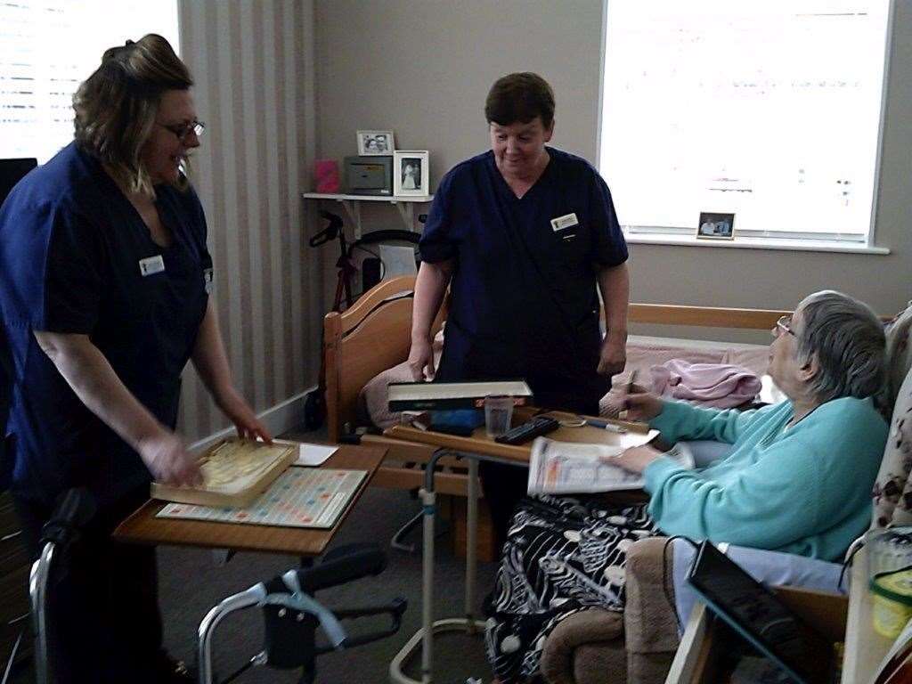 Resident Jean Kemlo playing a game of scrabble with care home workers