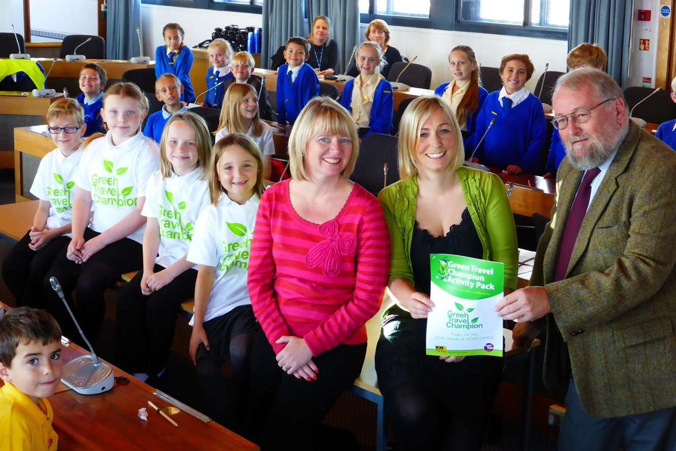 Thanet launch of the Green Champions initiative at Thanet Council chambers. Stuart Smith, Trustee of the KM Charity Team, presents Thanet Council air pollution expert Amanda Berry with a copy of the Green Champion delegate pack, watched by event chairman Karen Brinkman (left of main group) and child delegates attending the event