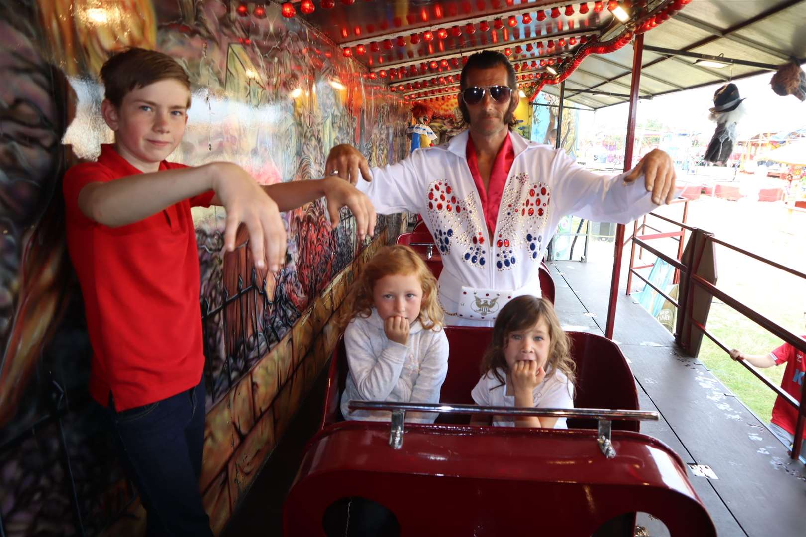 All shook up: Elvis Daniel Aylwin, 46, from Sheerness creates a song and a dance on the Graveyard Express ghost train at Leysdown, Sheppey, watched by the train's station master Reece Brett, 12, and guinea pigs Darcey Christian, 6, and her cousin Crystal Christian, 4. Picture: John Nurden
