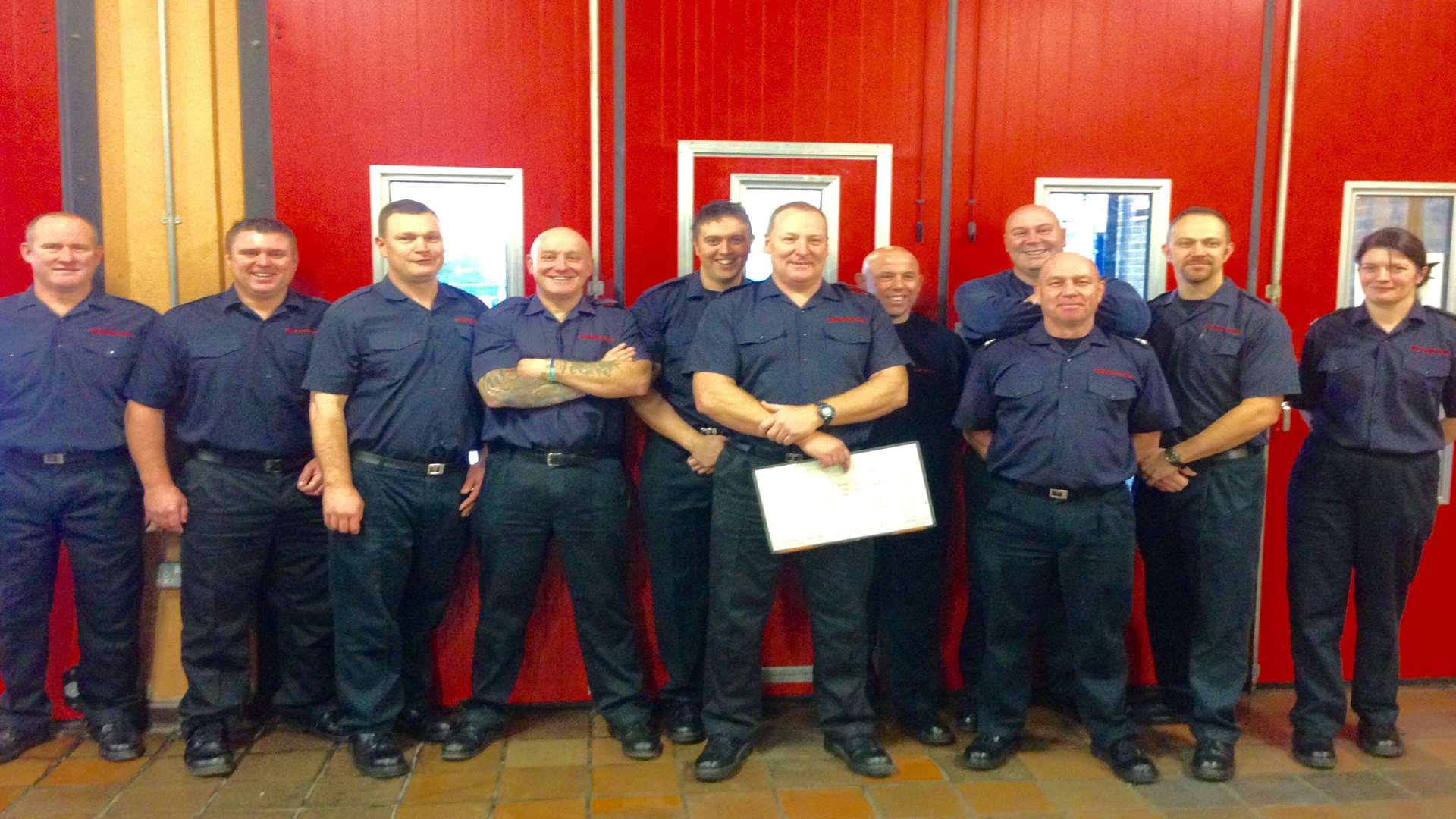 Dave Mayhew (front with white paper) and colleagues on his last day at the fire station
