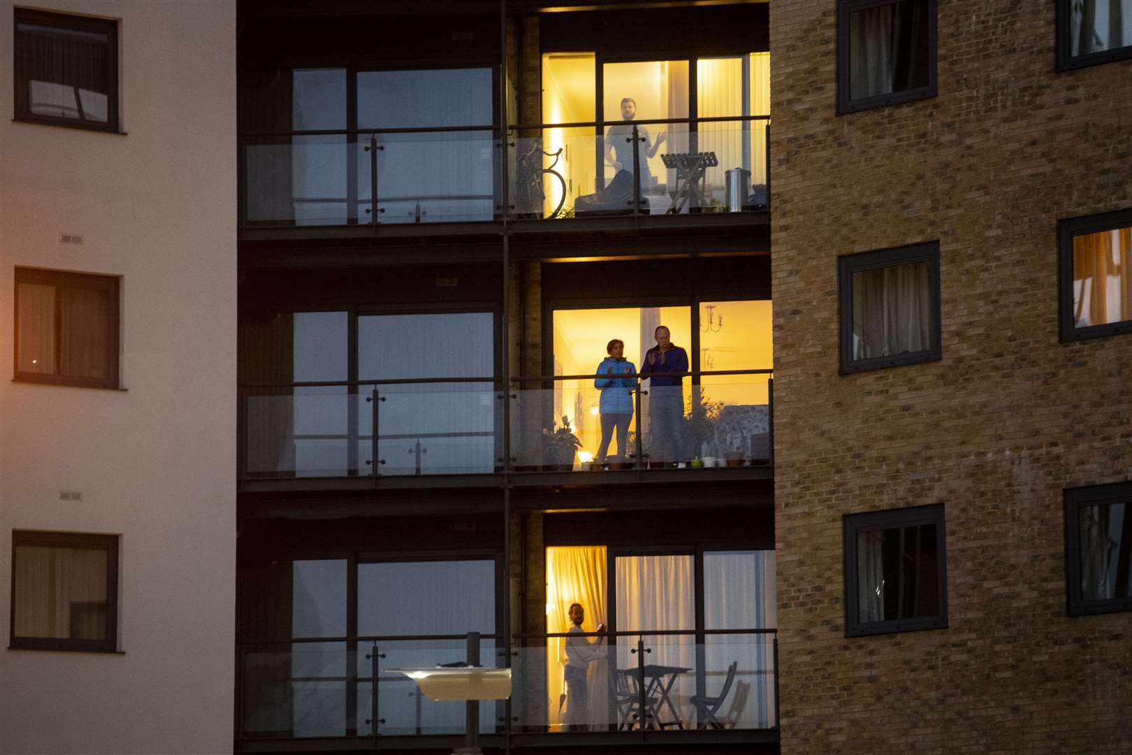 Members of the public clap on their balconies in Canary Wharf, to salute NHS staff (Victoria Jones/PA)