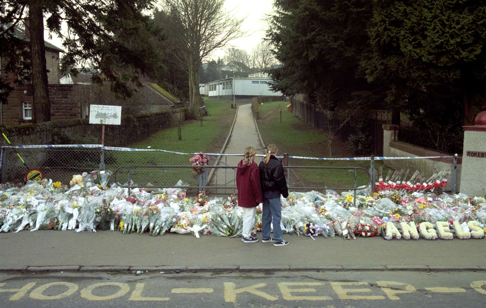 Two children stand in front of a floral tribute to the victims of the Dunblane massacre (Stefan Rousseau/PA)