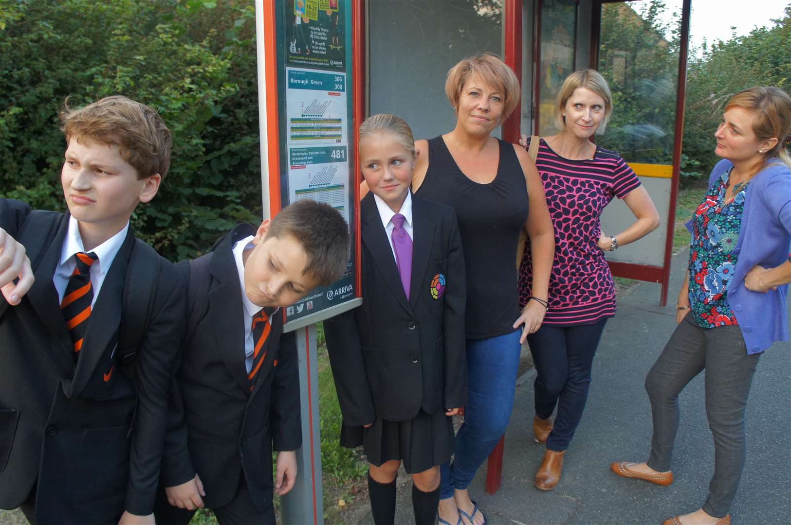 (L/R) Dennis Hughes, 11, Christian Timothy, 11, Ellise Ayres, 11, Lisa Ayres, Estelle Timothy, Joanna Hughes waiting at the bus stop