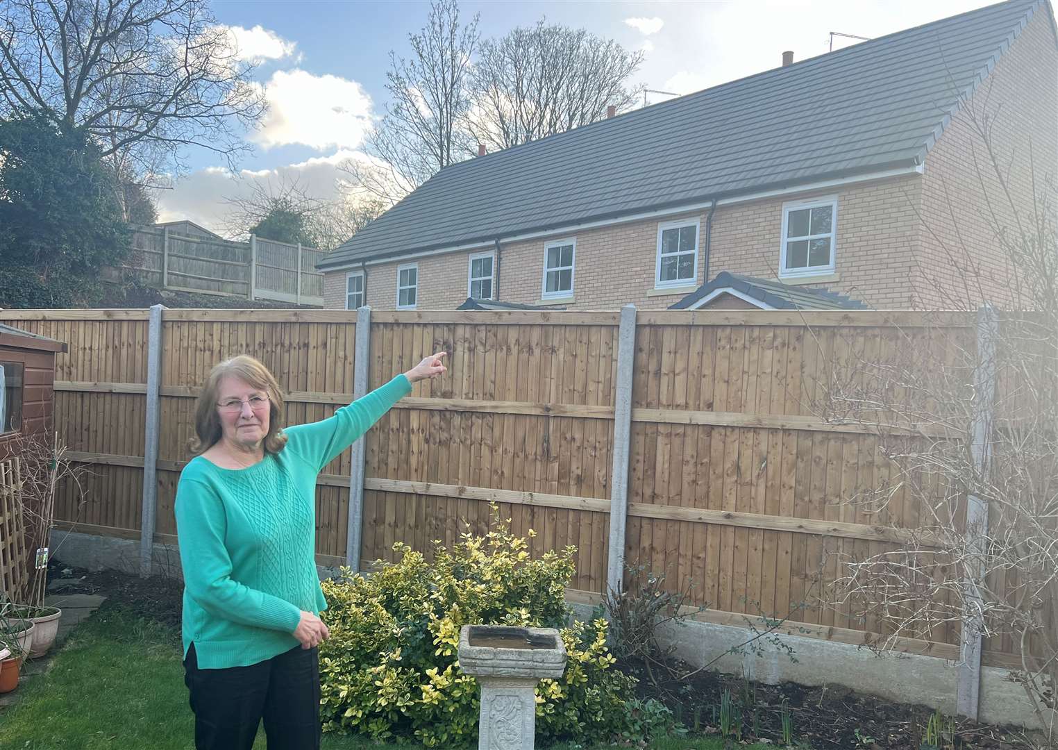 Ann Smith in her back garden in Lydbrook Close, Sittingbourne, pointing at the wrongly positioned Moat Homes new builds