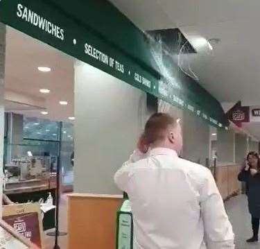 Staff and customers look on as water pours from the ceiling into the store