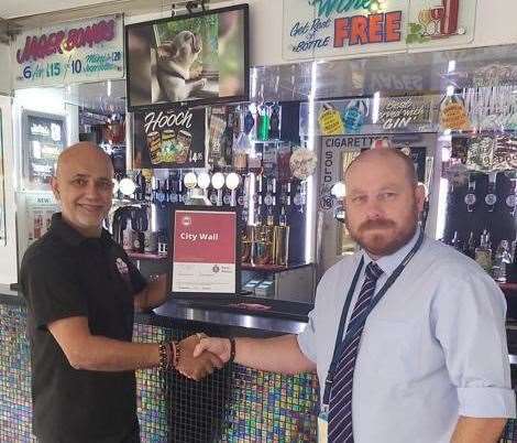 Sanjay Raval (left) from City Wall Wine Bar, receiving the Best Bar None Award from Kent Police's licensing team